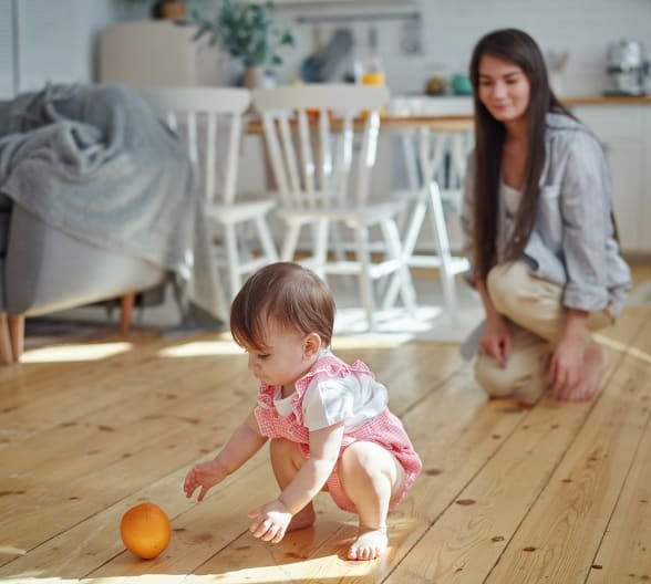 A mother and her baby playing on a hardwood floor